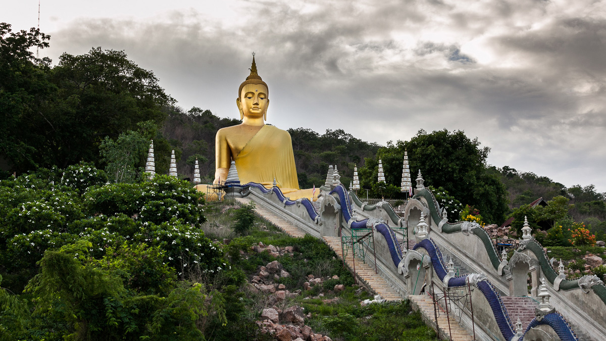 A golden Buddha statue nestled on a hillside.