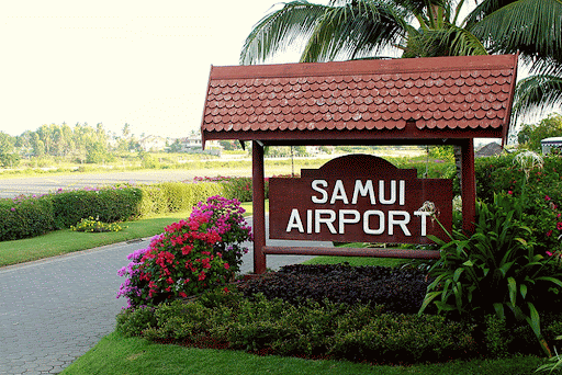 Dark brown wooden sign with white lettering dispaying 'Samui Airport'